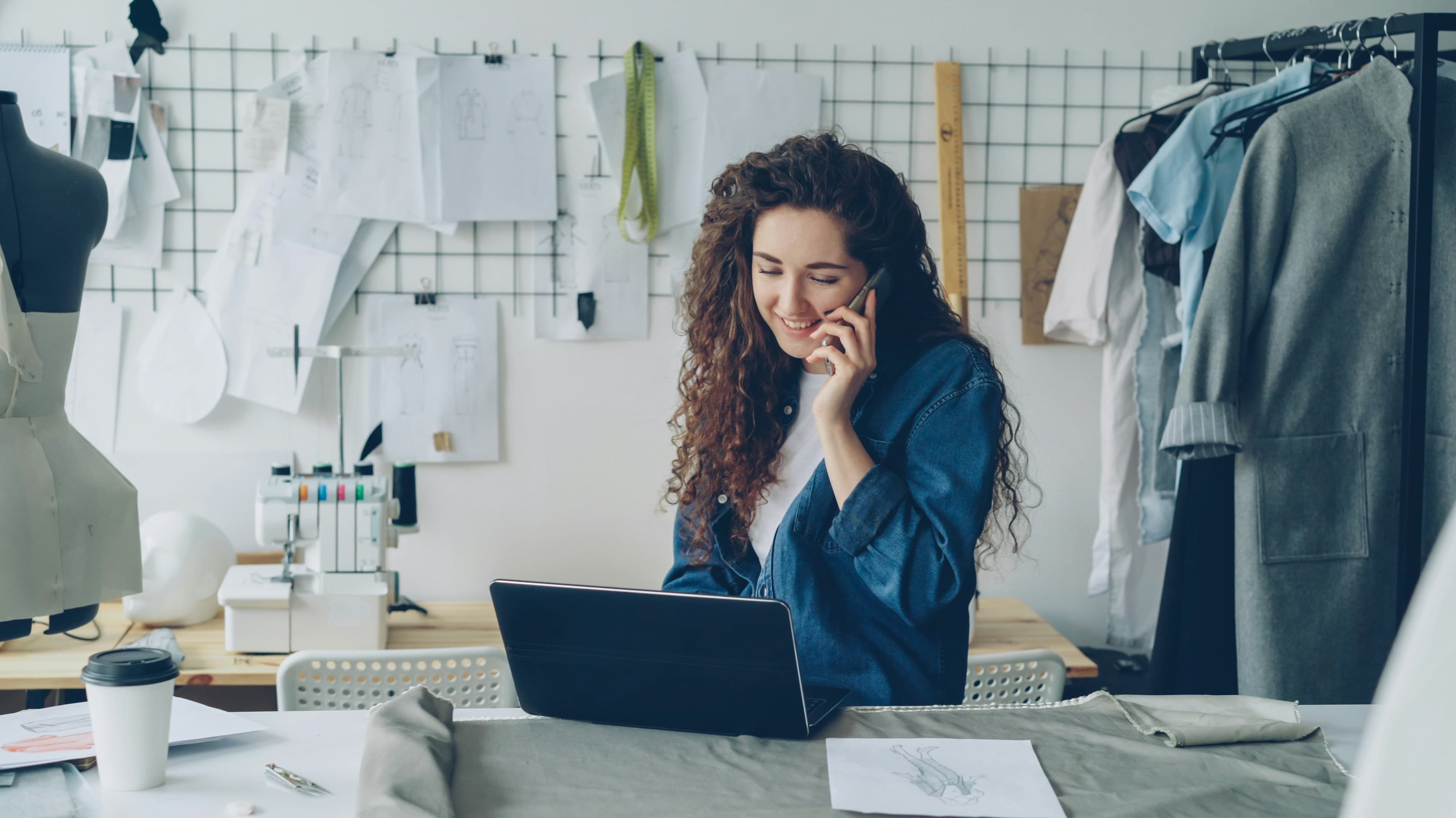 Empreendedora ao telefone enquanto trabalha no notebook